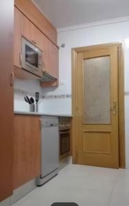 una pequeña cocina con puerta y microondas en La Escapada, en Posada de Llanes