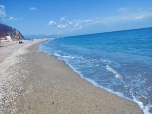 a beach with blue water and a rocky shoreline at Bergeggi frontemare - Condominio soggiorno al mare in Bergeggi