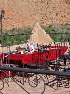 un tavolo con una tovaglia rossa e sedie su una montagna di Kasbah des montagnes maison d'hôtes a Bou Drarar