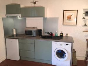 uma cozinha com uma máquina de lavar roupa e um micro-ondas em Gîte 2-4 couchages situé dans un magnifique jardin em Saint-Vivien