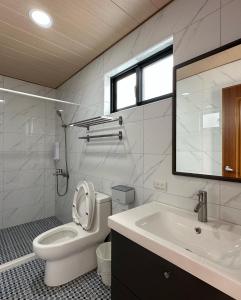 a white bathroom with a toilet and a sink at Second Hostel in Xiaoliuqiu