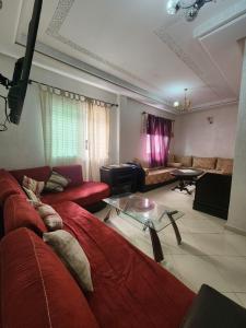 een woonkamer met een rode bank en een glazen tafel bij Le Coin Appart in Kenitra