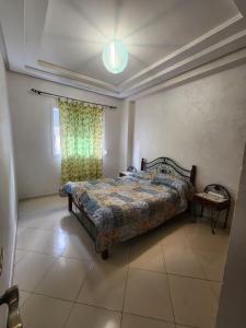 een slaapkamer met een bed, een tafel en een raam bij Le Coin Appart in Kenitra