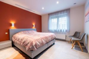 1 dormitorio con cama, ventana y silla en Vakantiewoning De Bles en Avelgem