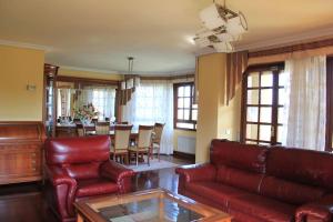 sala de estar con muebles de cuero rojo y comedor en Villa Marta, en Santillana del Mar