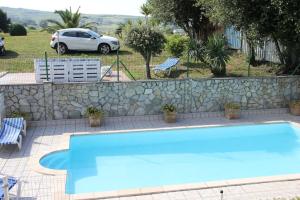 ein großer blauer Pool neben einer Steinmauer in der Unterkunft Villa Marta in Santillana del Mar