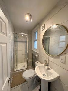 y baño con aseo, lavabo y espejo. en Pink Door Guesthouse, en Londres