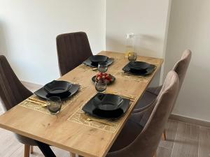 une table en bois avec des assiettes noires et des verres dans l'établissement Anchor Apartments, à Shëngjin