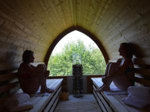 two people sitting on benches in a room with a window at Les Ventoulines in Domme