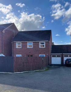 a red brick house with a fence in a parking lot at Spacious 8 bed house Kirkby in Ashfield Nottingham in Kirkby in Ashfield