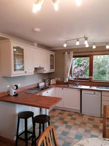 a kitchen with white cabinets and a wooden counter top at Brackenbrae Holiday Cottage in Acharacle