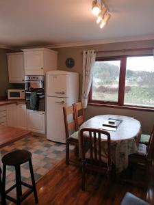 a kitchen with a table and chairs and a refrigerator at Brackenbrae Holiday Cottage in Acharacle