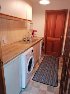 a kitchen with a washing machine and a sink at Brackenbrae Holiday Cottage in Acharacle