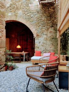 un patio con sillas, una mesa y una pared de piedra en CAN TANDO Restored catalan old barn to enjoy peaceful rural simplicity, en Sant Jordi Desvalls