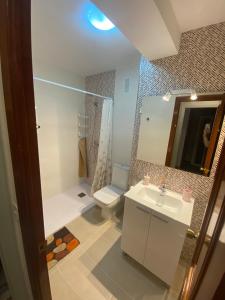 y baño con lavabo, aseo y espejo. en Apartamento céntrico con vistas y cerca de playa, en Puentedeume