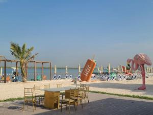 a table and chairs on the beach next to the beach at Luxury apartment in Yas Island in Abu Dhabi