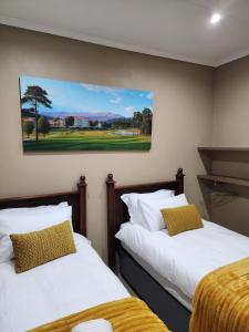 two beds in a room with a painting on the wall at @Merino in Ermelo