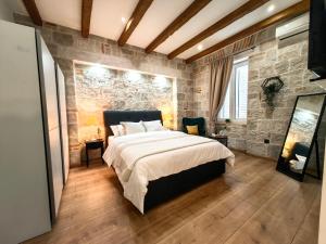 - une chambre avec un grand lit et un mur en pierre dans l'établissement Apartments Lana Spalato, à Split