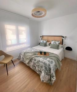 a white bedroom with a bed and a chair at Apartamento La Muralla in Talavera de la Reina