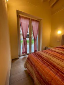 a bedroom with a bed and a window with pink curtains at Casa Tortora in Gravedona