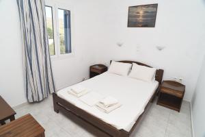 a bedroom with a bed with white sheets and a window at Joanna Apartments in Mikri Vigla