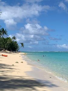 einen Strand mit Menschen, die im Meer schwimmen in der Unterkunft Konini Retreat in Rarotonga