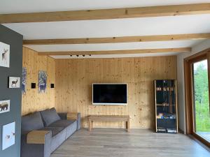 a living room with a couch and a tv on a wall at WALDHAUS HIRSCH Bungalow only for you self check in in Pörtschach am Wörthersee