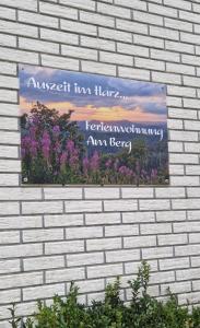 un panneau sur le côté d'un mur de briques avec des fleurs dans l'établissement Ferienwohnung Am Berggipfel, à Wieda