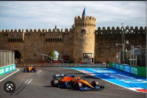 two race cars on a track in front of a castle at Hotel Empire Business Baku in Baku