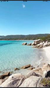 a beach with blue water and rocks on the shore w obiekcie Mini villa proche des plus belles plages w mieście Porto-Vecchio