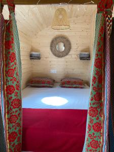 uma cama num quarto de madeira com cortinas vermelhas em Les Roulottes de l Herm Piscine Jacuzzi Perigord em Rouffignac Saint-Cernin