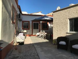 a patio with two chairs and an umbrella at Casa o Futuro in Alcobaça