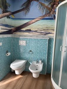 a bathroom with a toilet and a sink with a picture of the beach at CA' del GIACOMINO in Baselga di Pinè