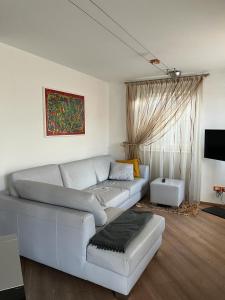 sala de estar con sofá blanco y TV en CA' del GIACOMINO, en Baselga di Pinè