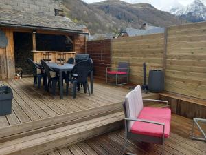 una terraza de madera con mesa y sillas. en Maison familiale au centre de Loudenvielle, en Loudenvielle