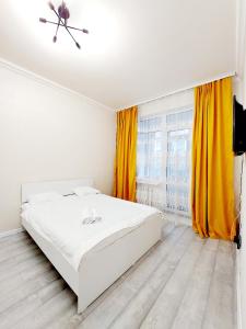 a bedroom with a white bed and yellow curtains at ЖК Сапфир центр столицы in Taldykolʼ