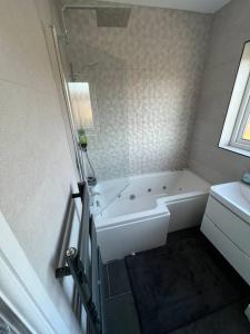 a white bathroom with a tub and a sink at Gants hill in Barkingside