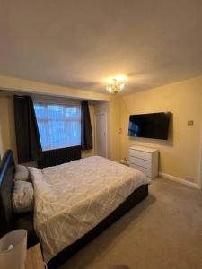 a bedroom with a bed and a flat screen tv at Gants hill in Barkingside