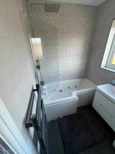 Baño blanco con bañera y lavamanos en Gants hill en Barkingside