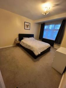 a bedroom with a bed and a window and a chandelier at Gants hill in Barkingside