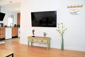 Una sala de estar con una mesa y un televisor en una pared. en Terraza privada MarDeLunas, en El Bosque