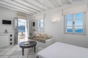 a white bedroom with a bed and a couch at Archondoula Studios in Plaka Milou