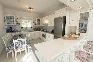 eine Küche mit weißen Schränken, einem Tisch und einem Kühlschrank in der Unterkunft Rigos House at Askeli beach, Poros island in Poros