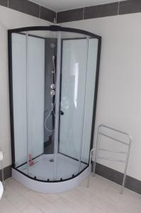 a shower with a glass enclosure next to a chair at Le Cosy in Sousceyrac