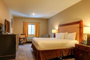 Schlafzimmer mit einem Bett, einem Schreibtisch und einem Fenster in der Unterkunft Wagon Wheel Hotel in West Yellowstone