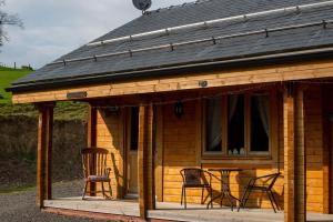 une cabine avec des chaises et une table sur une terrasse couverte dans l'établissement APPLE Cabin - Little Log Cabin in Wales, à Newtown