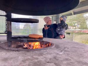 two people standing next to a grill with a hot dog at Huoneistomajoitus Pirtti, LaatuLomat in Juva