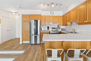 a kitchen with wooden cabinets and a stainless steel refrigerator at Blue Mountain Ski In Ski Out Resort Condo 2 Level in Blue Mountains