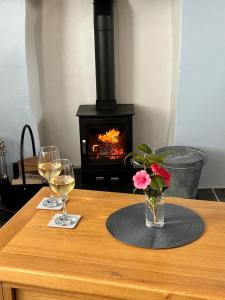 a table with two glasses of wine and a fireplace at Pendragon in Penzance