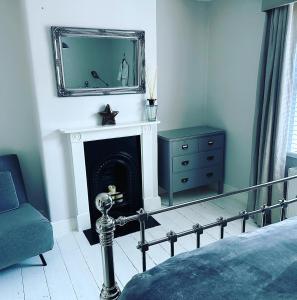 a bedroom with a fireplace with a mirror and a chair at Spa Cottage Weymouth in Weymouth